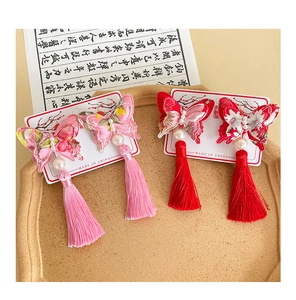 Detail of embroidered butterfly hair clips with pearls and tassels on a vintage tray