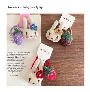 Détail des charms lapin en peluche et fraise tricotée sur élastiques à cheveux