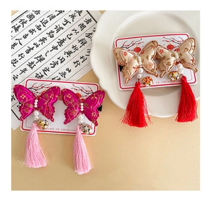 Close-up of butterfly embroidery hair clip with pearls, bells and long silk tassels
