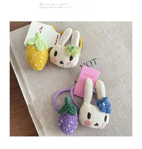 Détails de charms tricotés en forme de fraise et lapin sur des élastiques à cheveux