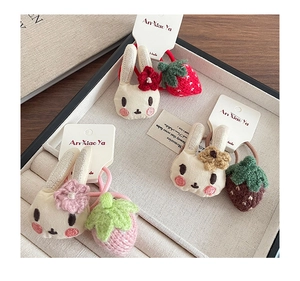 Détails d'élastiques à cheveux faits main lapin et fraise dans un coffret à bijoux beige