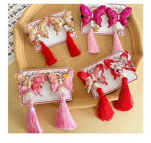 Detail of embroidered butterfly hair clips with pearls and long tassels in four colors