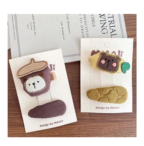 Detailed close-up of handmade fabric hair clips with cute bear embroidery on card