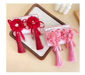 Détail de pinces à fleurs tricotées rouges et roses avec pompons de soie et grelots