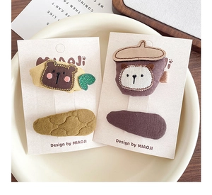 Detail of handmade embroidered fruit bear hair clips for girls on display card