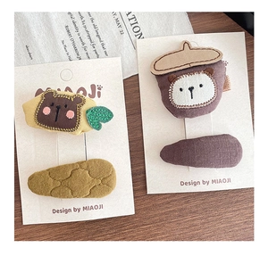 Detail view of handmade fabric hair clips featuring embroidered bears and acorn designs