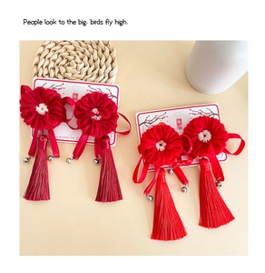 Détail de pinces à cheveux fleurs rouges tricotées avec pompons soie et grelots métal