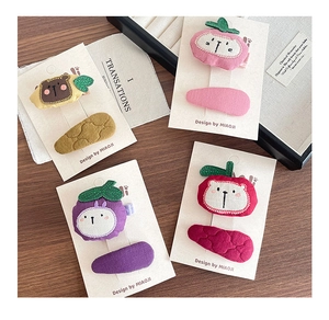 Detail of four sets of children's fabric hair clips with animal embroidery on wooden table