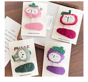 Detail of handmade fabric fruit hair clips with embroidery on white card packaging