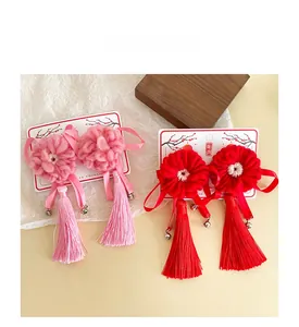 Détail de pinces à cheveux en laine faites main avec fleurs rouges, glands et cloches