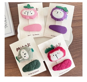 Detail of handmade padded fabric hair clips with embroidered cartoon fruit and animal faces