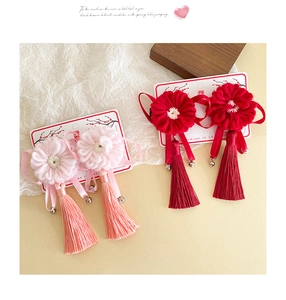Détail de pinces à cheveux fleurs tricotées avec longs pompons et clochettes