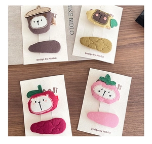 Detailed close-up of handmade fabric fruit animal hair clips for girls on wood background