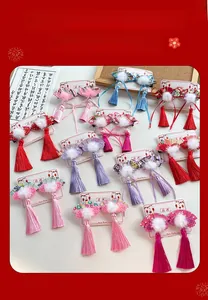 Detail view of traditional Chinese fan-shaped hair clips with tassels and pom-poms for girls