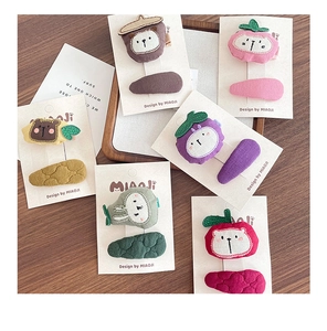 Detailed view of handmade fabric hair clips featuring cute embroidered fruit and animal motifs