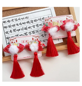 Detail of red Chinese fan hair clips with tassels and white pom poms for girls