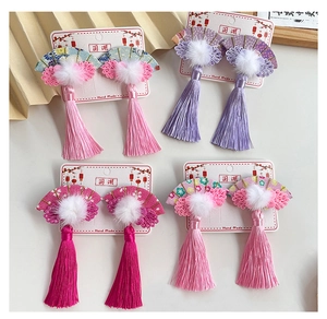 Detailed macro view of four traditional Chinese fan-shaped hair clips with silk tassels