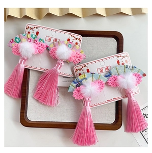 Detailed view of Chinese fan hair clips with soft white fur balls and pink tassels