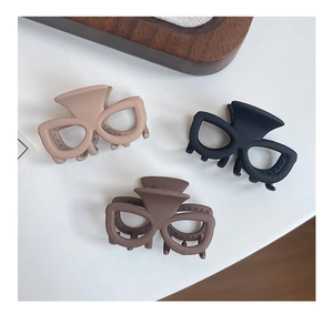 Détail de pinces à cheveux mates en forme de lunettes en beige, marron et noir chic