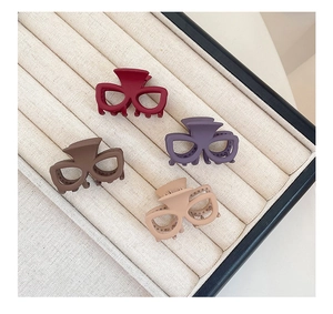 Détail de quatre pinces à cheveux mates en forme de lunettes en bordeaux, violet, brun et beige