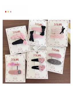 Detailed set of assorted pink fabric hair clips with floral and tweed patterns on wooden table