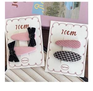 Detailed view of pink bow hair clips and houndstooth snap clips on display cards