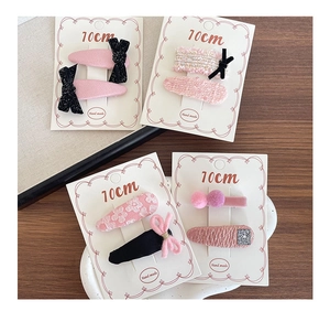 Detail of four sets of handmade pink fabric hair clips displayed on 10cm branded cards
