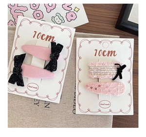 Close-up of pink fabric hair clips with black bows and 10cm wide display card