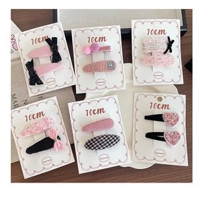 Detailed set of pink and black fabric hair clips featuring bows and houndstooth patterns