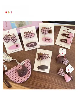 Gros plan de pinces à cheveux à nœuds écossais et accessoires en cœur sur table en bois