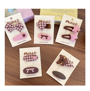 Détail de barrettes à carreaux avec nœuds et cœurs pour filles sur fond en bois vintage