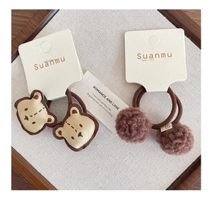 Dettaglio di elastici con testa d'orso ricamata e pompon soffici per bambine