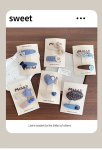 Detailed view of handmade blue fabric hair clips with star and heart knitted patterns
