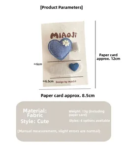 Detail of blue fabric heart hair clip and white oval clip for girls on paper card