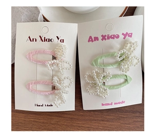Detailed macro view of handmade pink and green pearl bow hair clips on paper display card