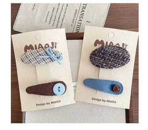 Detail of fabric hair clips with bows and buttons on a beige display card