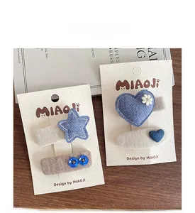 Detailed view of handmade blue fabric hair clips with star and heart patterns on card