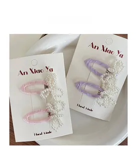 Detailed view of handmade pink and purple hair clips with beaded pearl bow designs