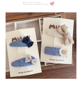 Detailed view of four-piece blue fabric hair clips with bows on wooden jewelry box