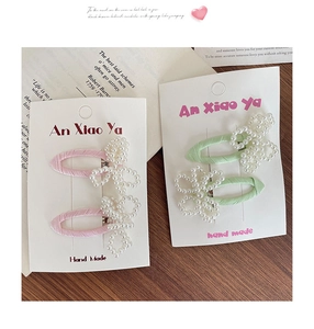 Detail of handmade pearl bow hair clips with pastel fabric bases on display card