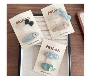 Detailed view of Morandi color fabric hair clips with embroidery, bows and wooden buttons