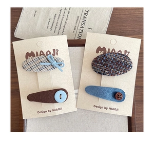Detailed set of four handmade fabric hair clips with bows and buttons on display cards