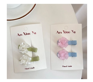 Detail of handmade fabric floral hair clips in pastel colors on a soft background