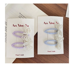 Detail of fabric wrapped hair clips with handmade pearl bow and beadwork on display card