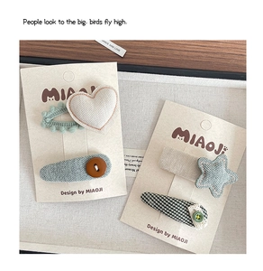 Detailed view of handmade fabric hair clips with heart and star patterns on display cards