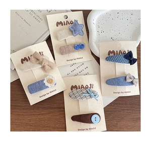 Detail of handcrafted fabric hair clips featuring blue bow, star and floral designs