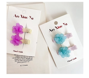 Close-up of floral hair clips with matte purple and blue petals on fabric base