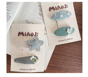 Detailed embroidery hair clips with star shapes and lace trim on a card display