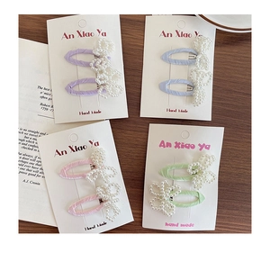 Detailed macro view of pastel pearl bow hair clips with hand-woven beads on fabric base