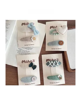 Detailed view of Morandi-colored knitted heart and bow hair clips on card packaging